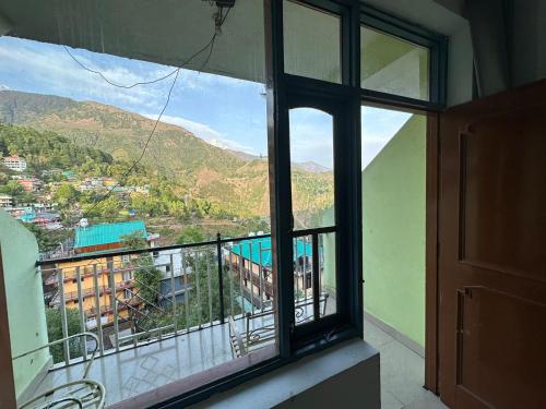 Room window framing the McLeod Ganj hillside village and distant mountains