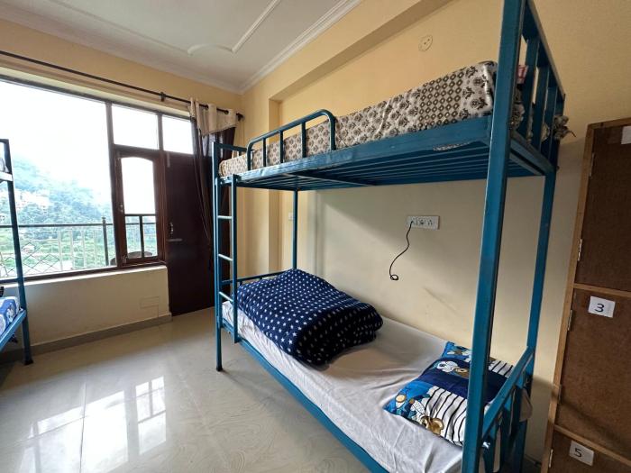 Numbered dorm bunks with blue star-print blankets and a balcony door in the background